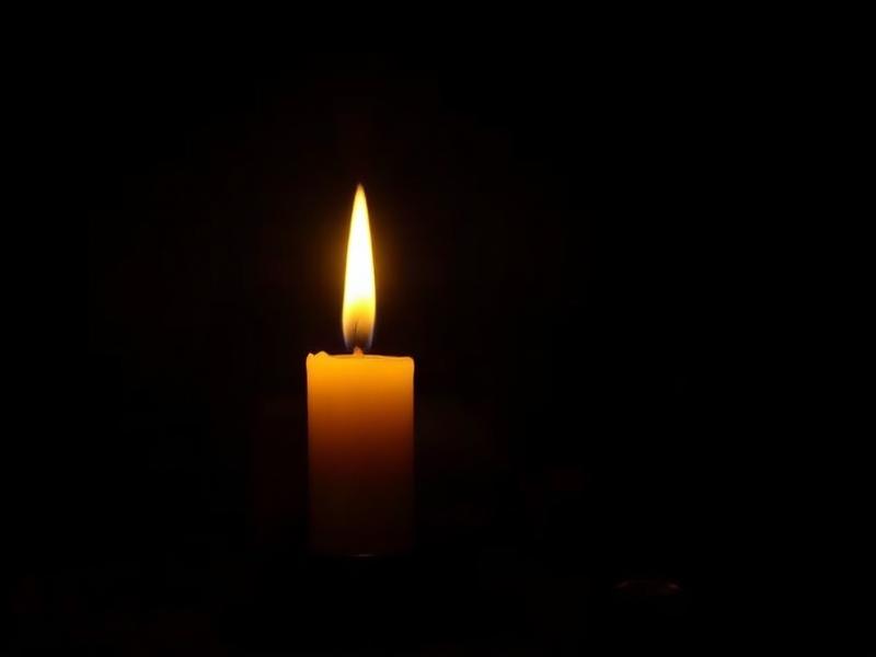 A single warm candle in a dark room